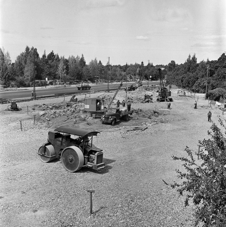 Runkolinjauuditukseen liittyvän bussien liittymäaseman rakentaminen Ruskeasuolle 1955, kaivinkone on ehkä Jussi 350 tai 200, numero on hytin ovessa mutta sitä ei näe tarkasti, takana Jones-nosturi, joka on kaupungin omistama kone ja sitä käytettiin usein työmailla, kuva: Okkola Bertel, Helsingin kaupunginmuseo.