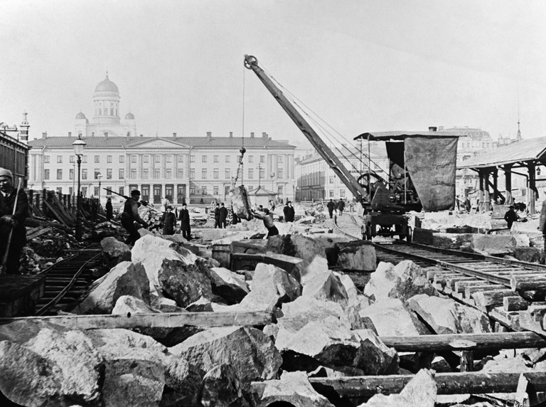 Satamarataa rakennetaan Kauppatorin kohdalla, nostokraana on höyryllä toimina ja muistuttaa ulkonäön puolesta 1800-luvun lopulla Helsinkiin ostettua Priestman-nosturia, joka saattoi olla ensimmäinen Suomeen hankittu maan kaivamiseen käytetty kone, kuva Johansson Otto, Helsingin kaupunginmuseo.