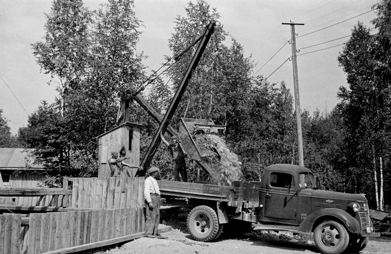 Kolmijalkanosturi oli paras keino nostaa kiviä tai maata syvästä montusta ennen kaivinkoneiden käyttöön ottoa. Tämä kuva on sota-ajalta ja siinä luultavasti on kysymys väestösuojan tai muun sodan kannalta tärkeän louhintatyön tekemisestä. Kuva Kannisto Väinö 1942, Helsingin kaupunginmuseo,