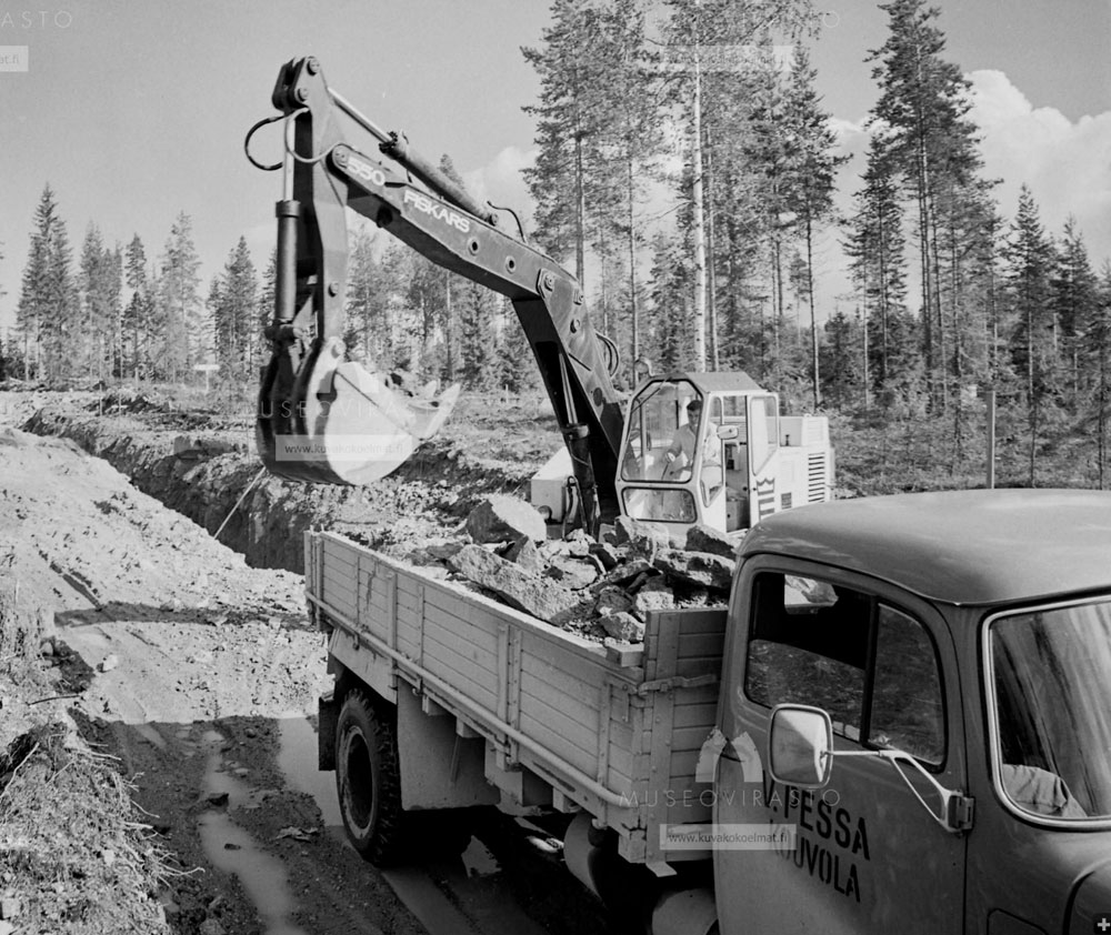 Museoviraston kuvia "kaivinkone nostamassa kiviä kuorma-auton lavalle Kouvolassa", Kyytinen Pekka 1972.