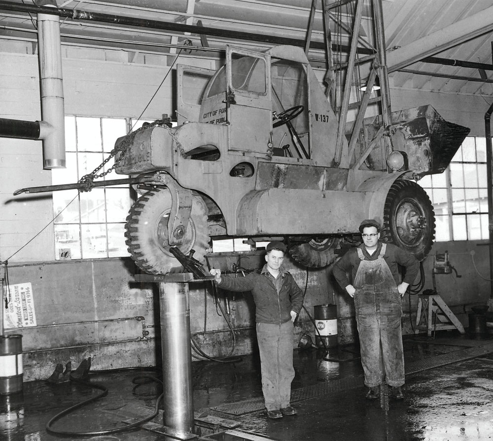 Two men with front loader on lift at Stanton Yard, circa 1955: A2005-005.403.2