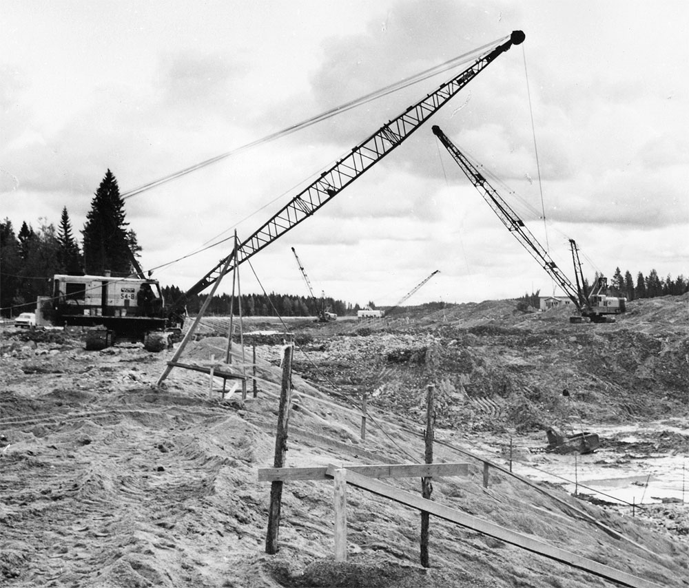 Kuvassa näkyvät koneet: Bucyrus-Erie 54-B Perusyhtymä (?), Lima 2400 Vesi-Pekka tai Perusyhtymä, ”Aleksi” eli tyyppi 4/40, missä 4 viittaa kauhan kokoon [m³] ja 40 puomin pituuteen [m] Vesi-Pekka, toinen Lima 2400, Kansola, Foto-Roos; Roos, Karl-Gustav, Saimaan kanava, Kansola : 451 (Liikennevirasto, 14.09.1966)